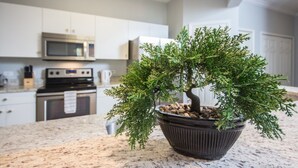 A kitchen with white cabinets, a microwave, and a potted plant on the counter. - Windsor Palms 2300 - 101 (Kissimmee)