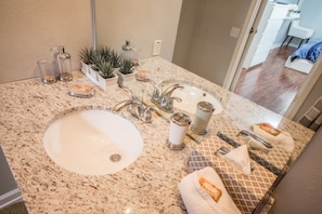 A bathroom with a granite countertop, a white sink, a mirror, and a potted plant. - Windsor Palms 2300 - 101 (Kissimmee)