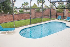 An indoor swimming pool with a brick wall and a glass enclosure.