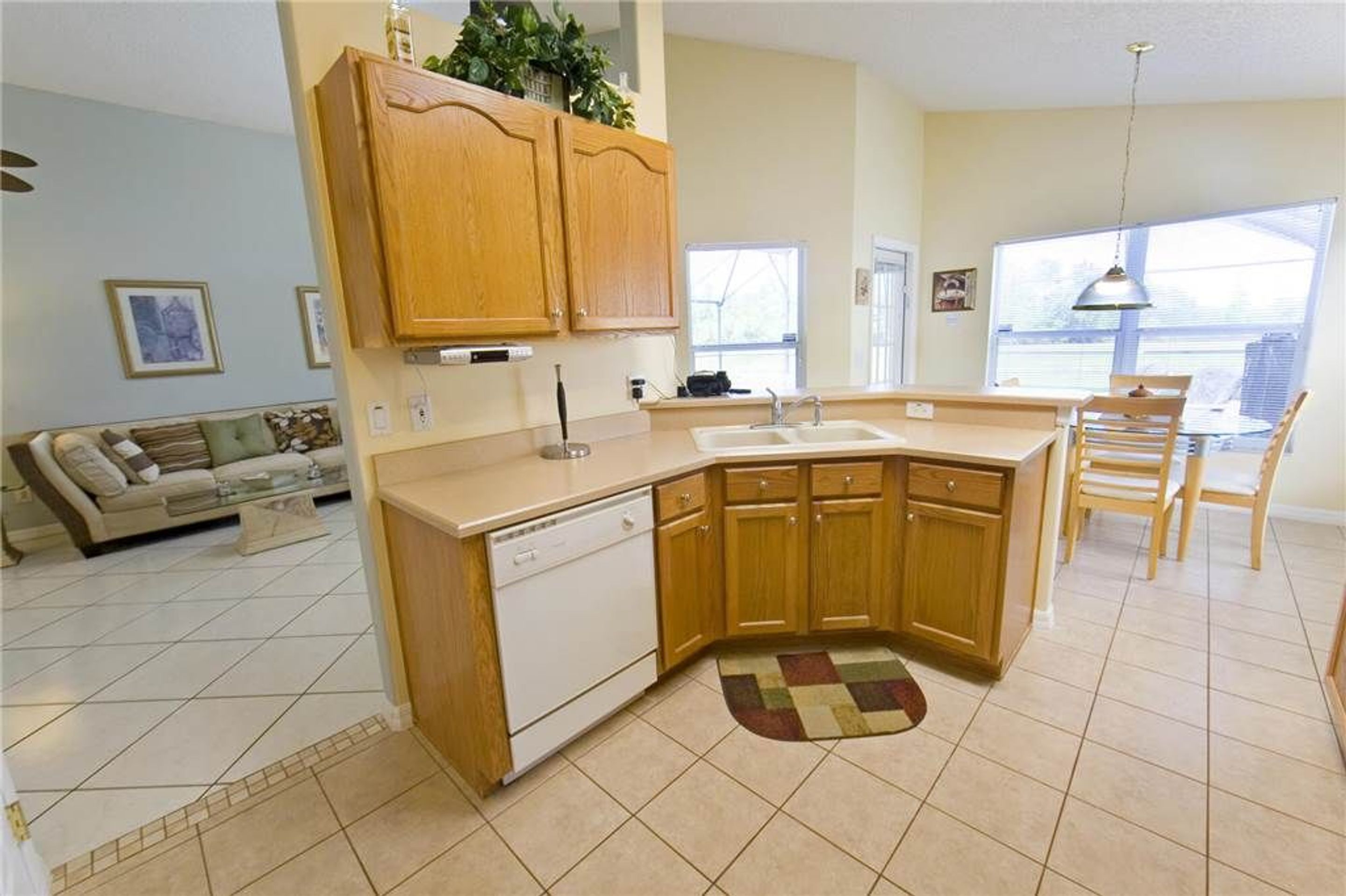 A kitchen with wooden cabinets, a dishwasher, and a dining area with a table and chairs.