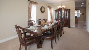 A dining room with a wooden table set for six, surrounded by chairs. - The Shire at West Haven 841 (Davenport)