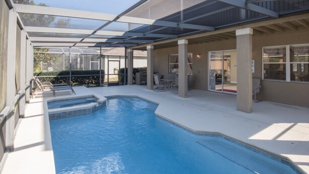 An indoor swimming pool with a glass enclosure, a sun terrace with seating, and a view of the outside. - The Shire at West Haven 841 (Davenport)
