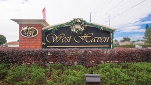A hotel sign with "West Haven" written in gold on a black background, surrounded by greenery and a brick structure. - The Hamlet at Westhaven 238 (Davenport)