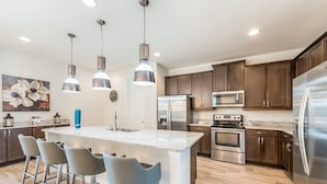 A modern kitchen with a central island, stainless steel appliances, and pendant lighting. - Encore Resort at Reunion 270 (Kissimmee)