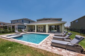 Área residencial com piscina, cadeiras de descanso e um alpendre coberto.