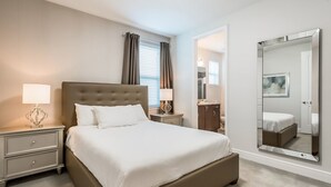 A neatly arranged bedroom with a large bed, bedside tables, a mirror, and a view into another room. - Encore Resort at Reunion 270 (Kissimmee)
