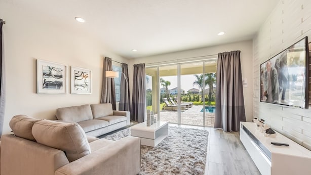 A modern living room with a beige sofa, a flat-screen TV, and artwork on the walls. - Encore Resort at Reunion 270 (Kissimmee)