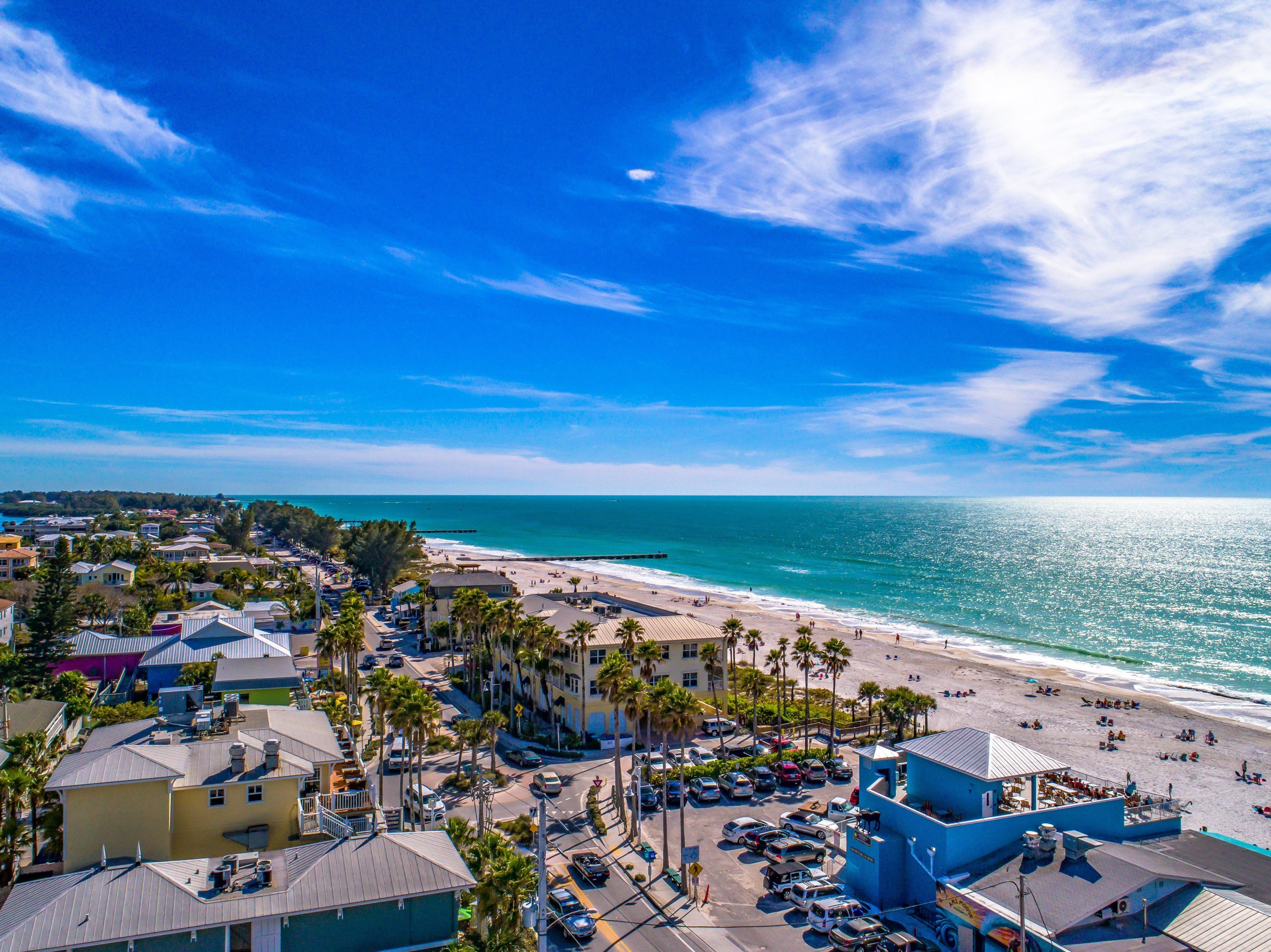 A coastal town with a beach, parked cars, and buildings with a mix of architectural styles.