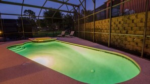 Una piscina esterna con idromassaggio, circondata da un recinto in vetro e pareti in pietra.