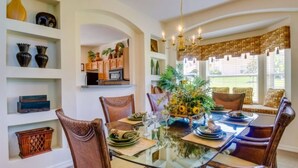 A dining area with a glass table, wicker chairs, and a floral centerpiece. - Emerald Island Resort 2801 (Kissimmee)