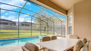 Eine überdachte Terrasse mit Pool, Tisch und Stühlen.