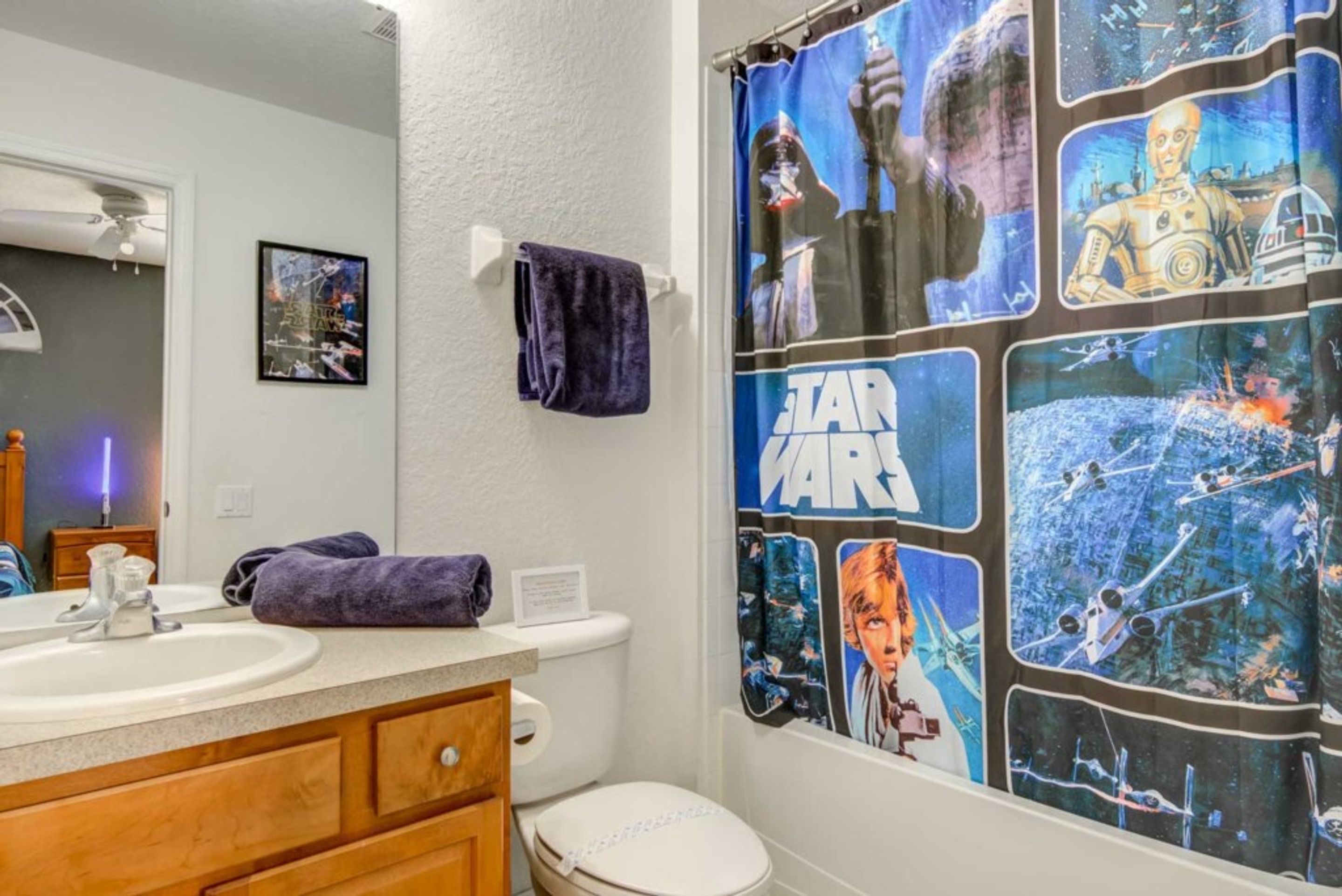 Une salle de bain avec un rideau de douche à l’effigie de Star Wars, un lavabo et des toilettes.