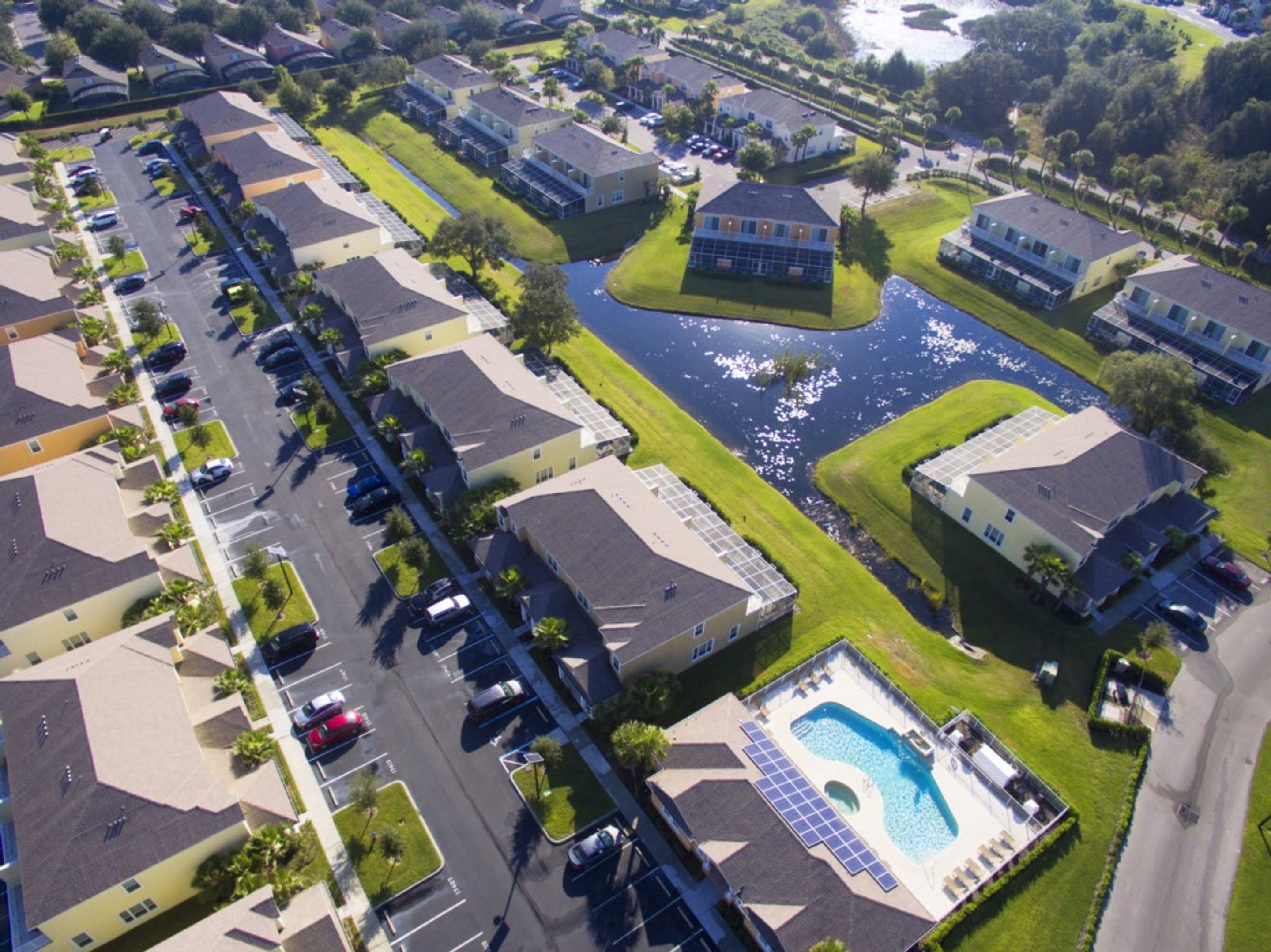 Vista aérea de una zona residencial con casas, piscina y una masa de agua.
