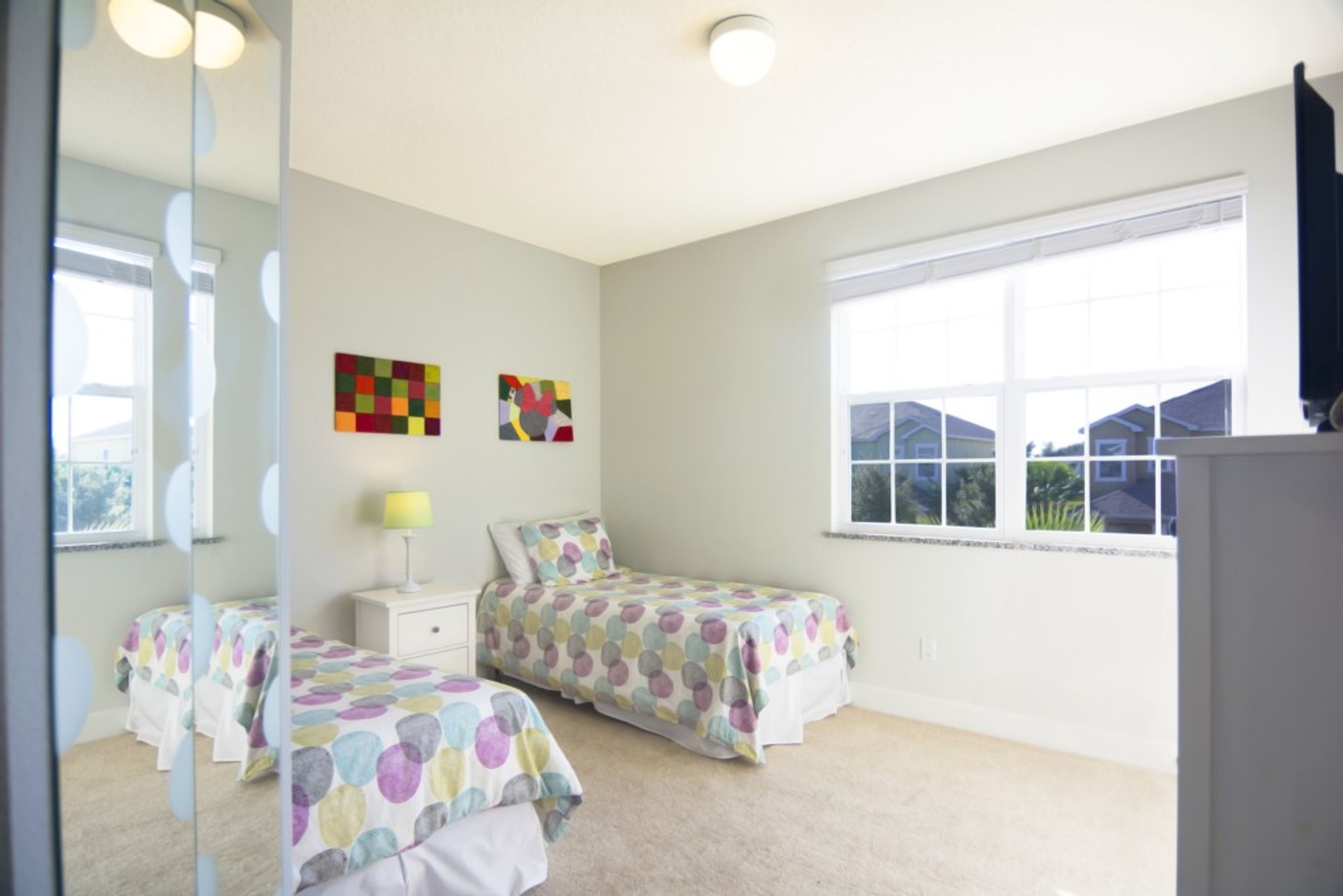 Une chambre avec deux lits, une fenêtre et des œuvres d’art accrochées au mur.