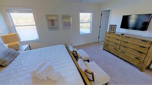 A bedroom with a bed, a bench, a dresser, a TV, and two windows. - Bella Vida 541 A (Kissimmee)