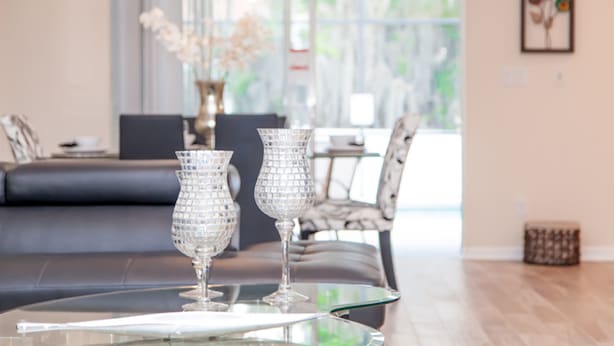 Un salon moderne avec une table basse en verre, deux vases en cristal, un canapé et un élément décoratif mural.
