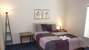 A neatly arranged bedroom with a bed, a bedside table, a bench, and two framed pictures on the wall. - Silver Creek 1217 (Clermont)