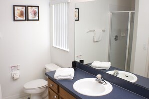 Ein Badezimmer mit Toilette, Waschbecken mit Spiegel und Duschbereich.