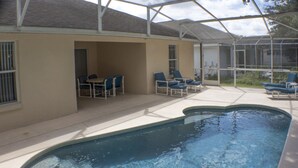 A swimming pool with lounge chairs and a covered patio area. - Silver Creek 1217 (Clermont)