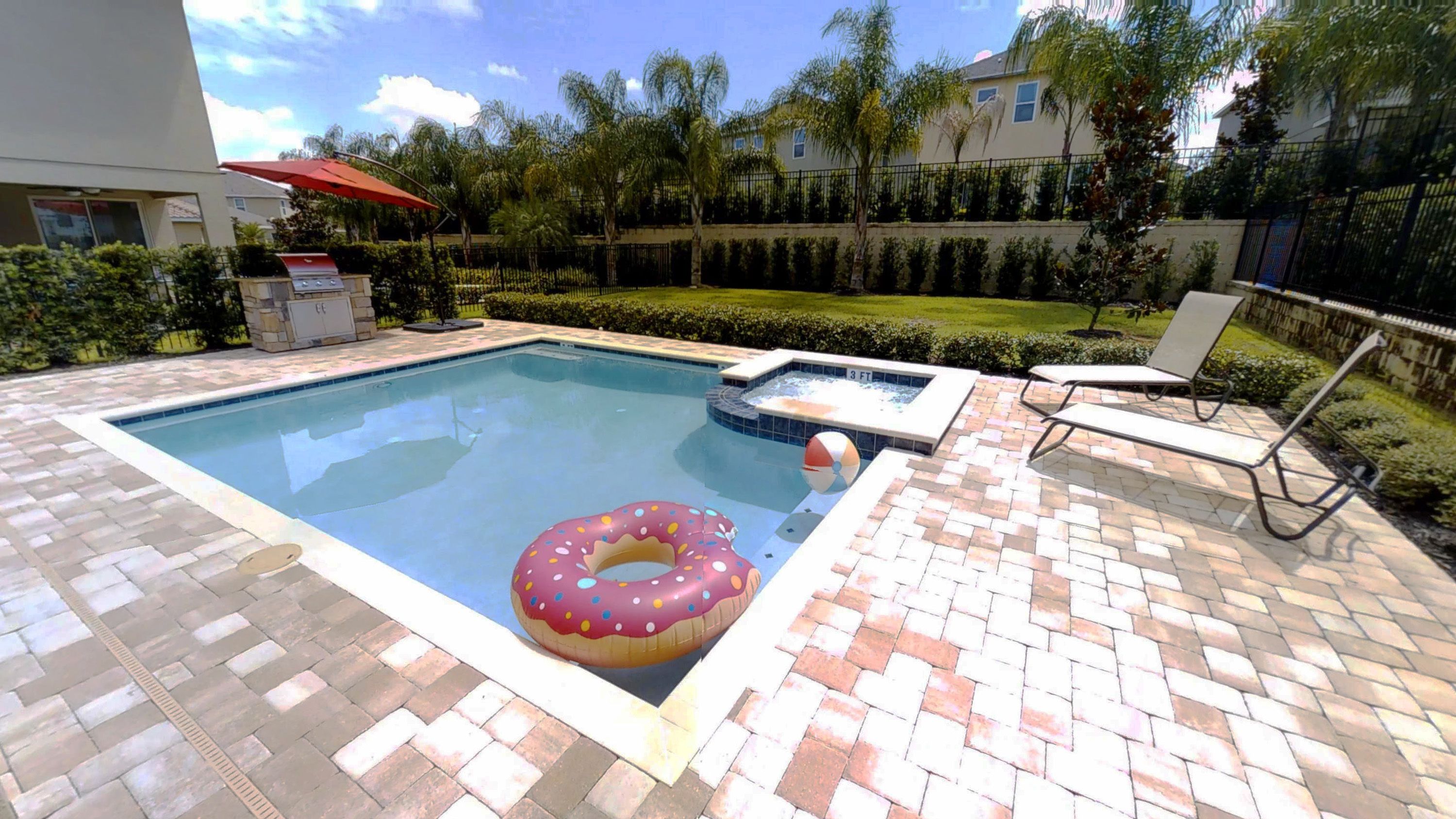 Une piscine avec un flotteur en forme de beignet, un jacuzzi et des chaises longues.
