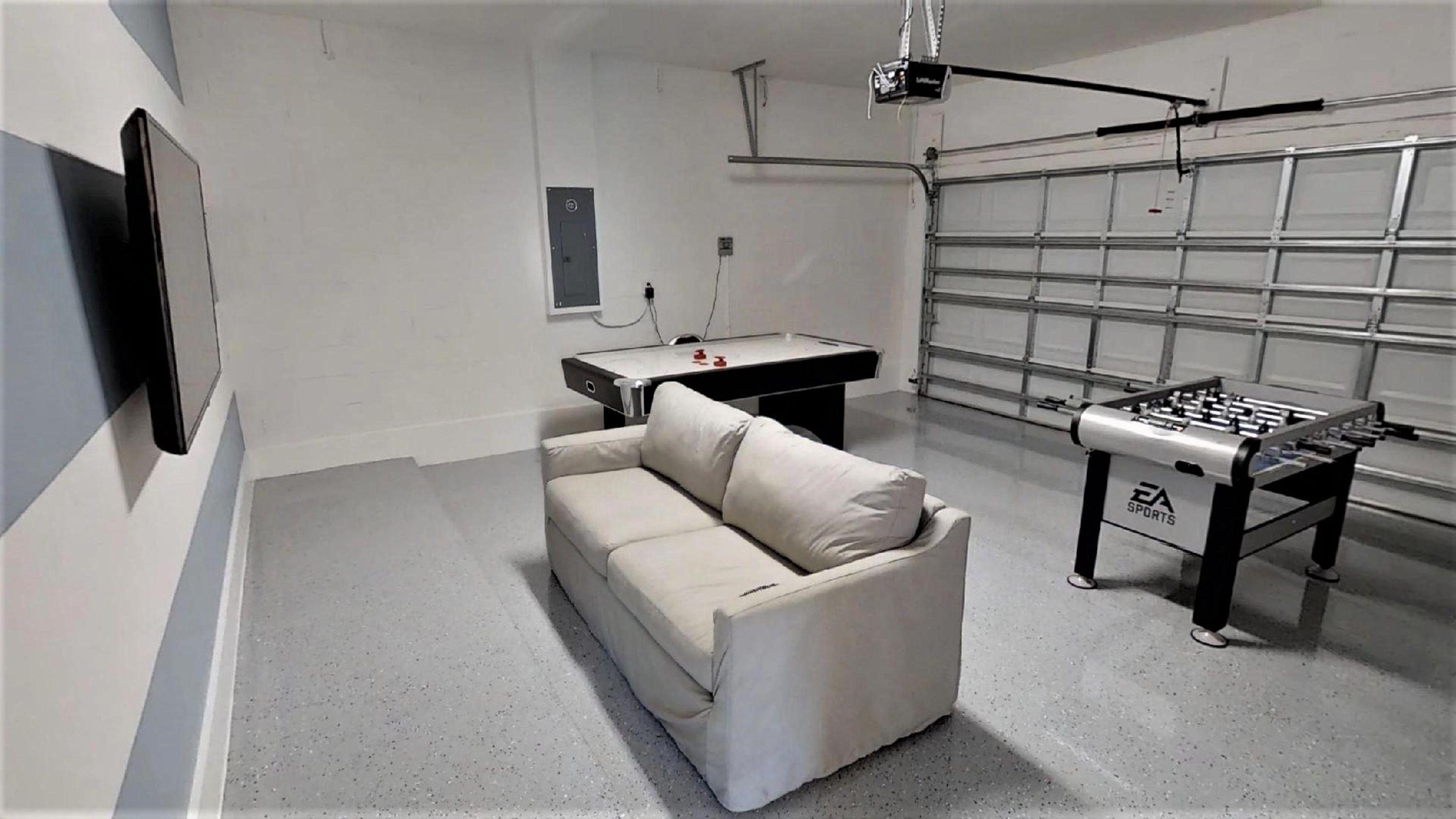 A room with a sofa, a foosball table, and a pool table.