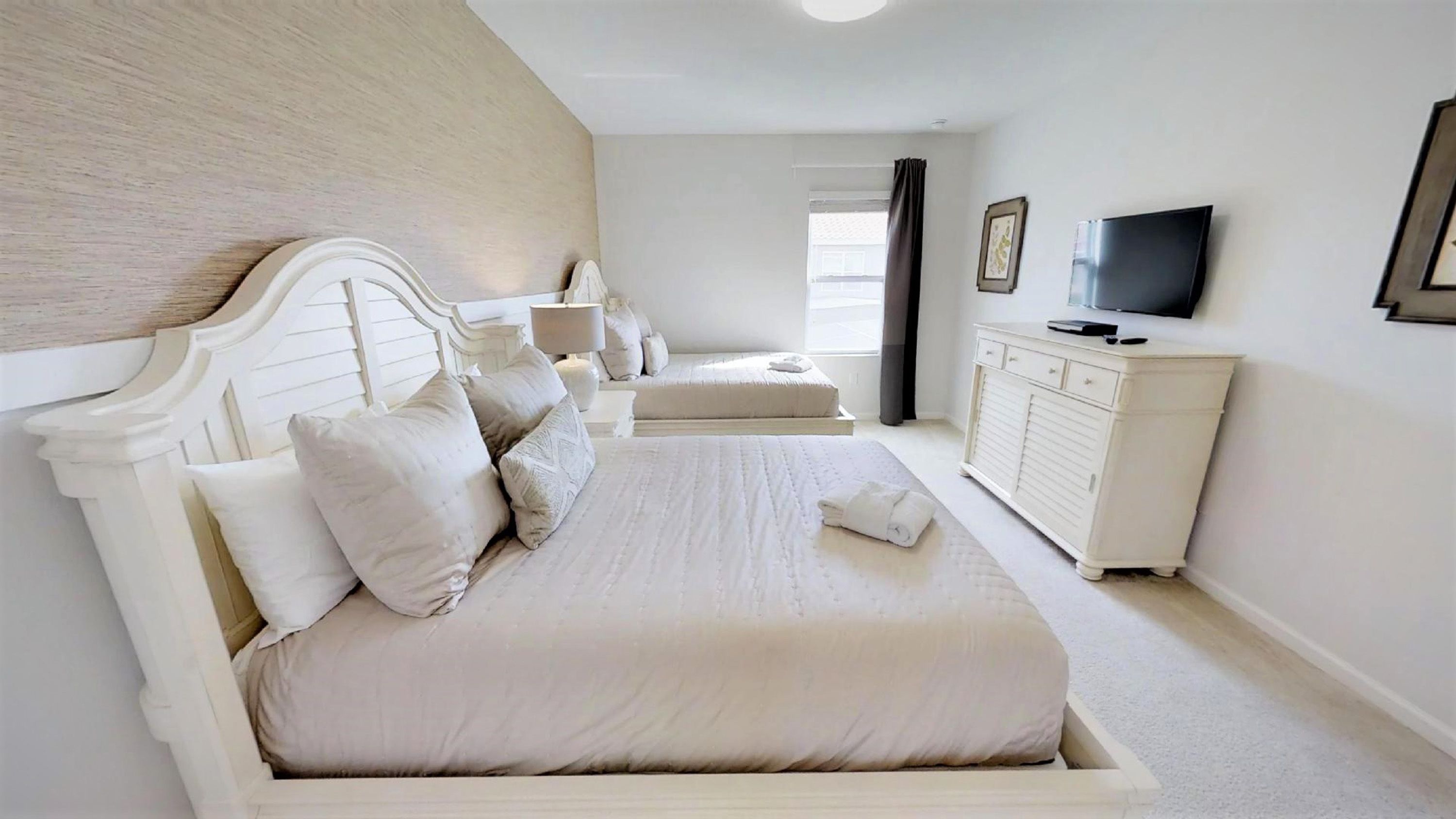 Une chambre à coucher avec un grand lit, une table de chevet, un téléviseur et une commode.