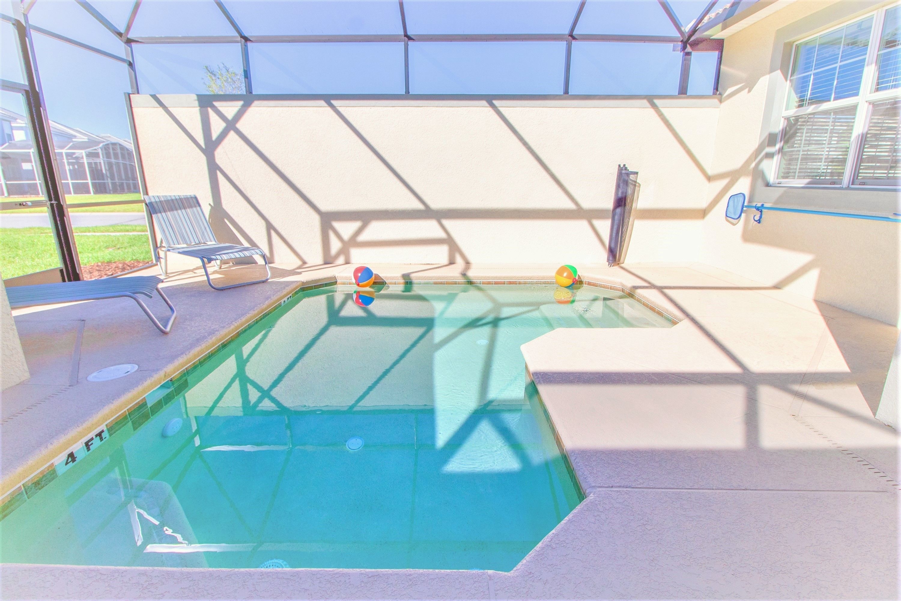 A swimming pool with a 4 ft depth marker, surrounded by a covered area with a bench and a window.