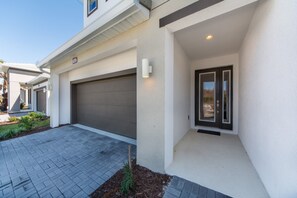 A modern house with a garage, a covered entryway, and a paved driveway. - Sonoma Resort 2682 (Kissimmee)