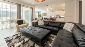 Ein modernes Wohnzimmer mit einem schwarzen Ledersofa, einem beigen Sessel und einem gemusterten Teppich.