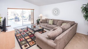 Een woonkamer met een bank, salontafel en een televisie op een standaard.