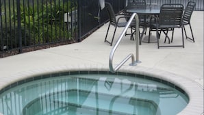 A hot tub with a metal ladder, surrounded by a tiled deck and a black metal fence. - Club Cortile 2730a (Kissimmee)