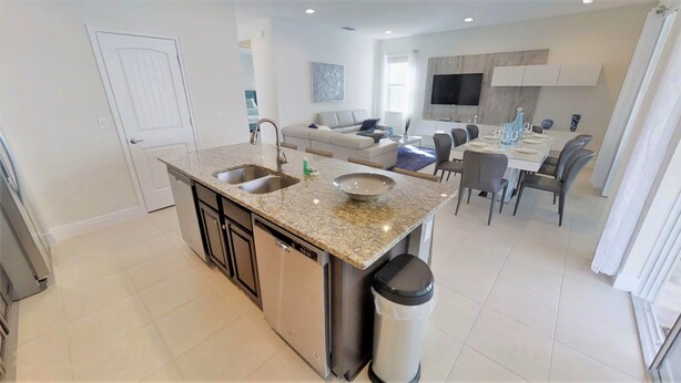 A modern kitchen with granite countertops, a dishwasher, and a trash can. - Encore Resort at Reunion 7407 (Kissimmee)
