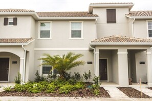 A row of townhouses with a central entrance, numbered 4971 and 4969, and a small palm tree in the front yard.