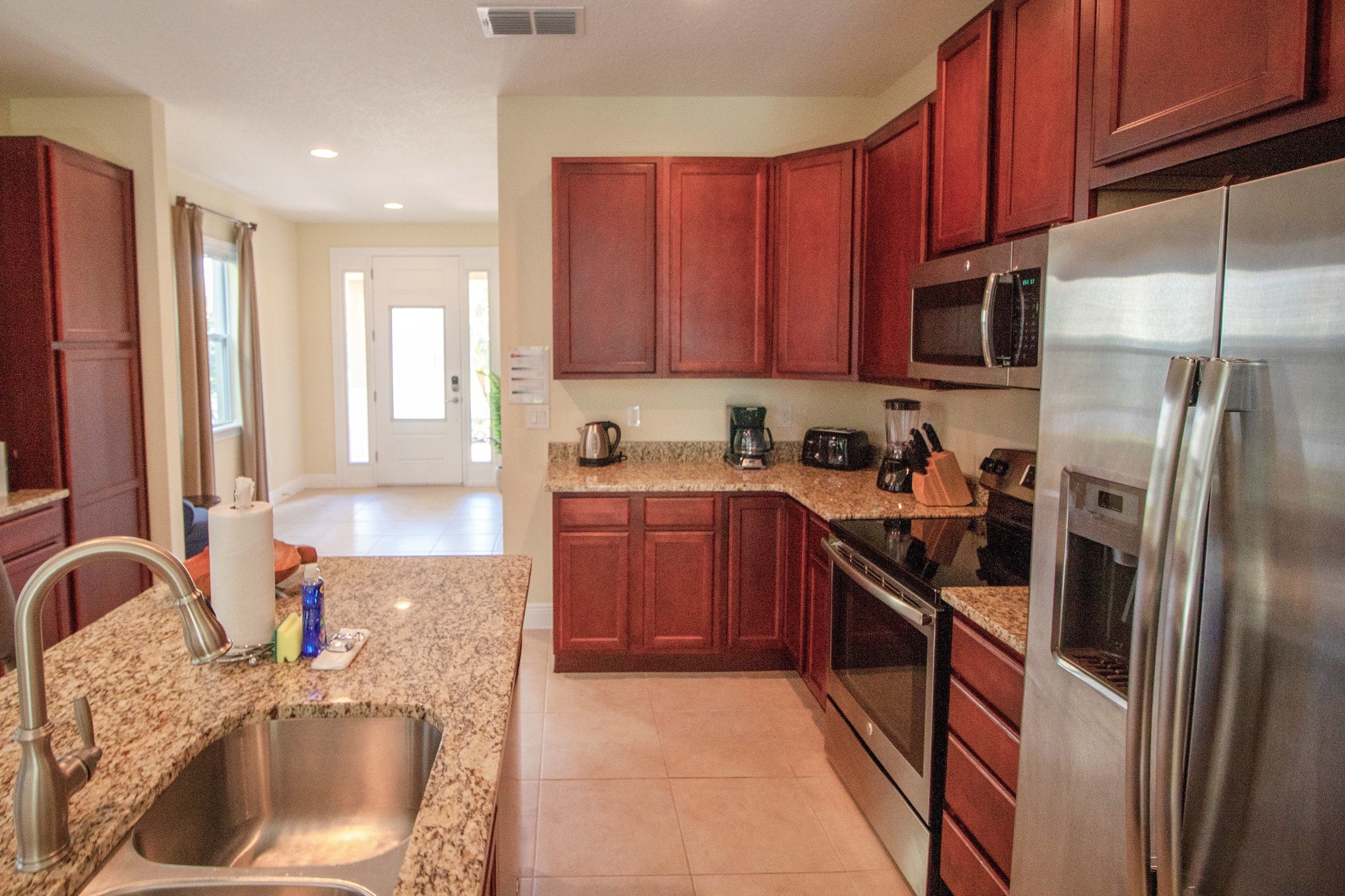 A modern kitchen with granite countertops, stainless steel appliances, and wooden cabinets.