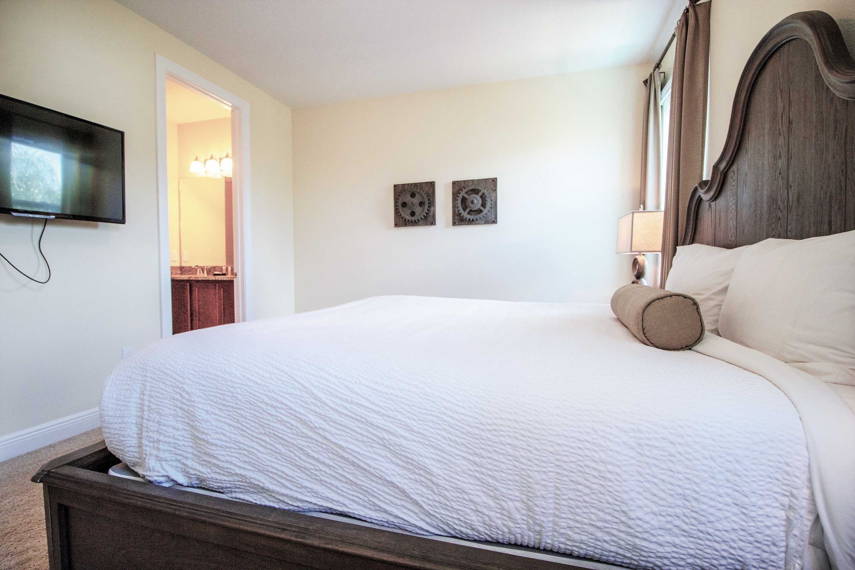 Camera da letto con un ampio letto, una TV a schermo piatto montata a parete e due applique.