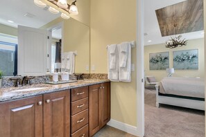 A bathroom with a granite countertop, wooden cabinets, a large mirror, and a chandelier. - Encore Resort at Reunion 7605 (Kissimmee)