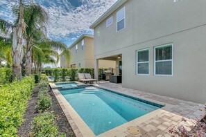 A residential building with a swimming pool, outdoor seating, and a covered patio area. - Encore Resort at Reunion 7605 (Kissimmee)