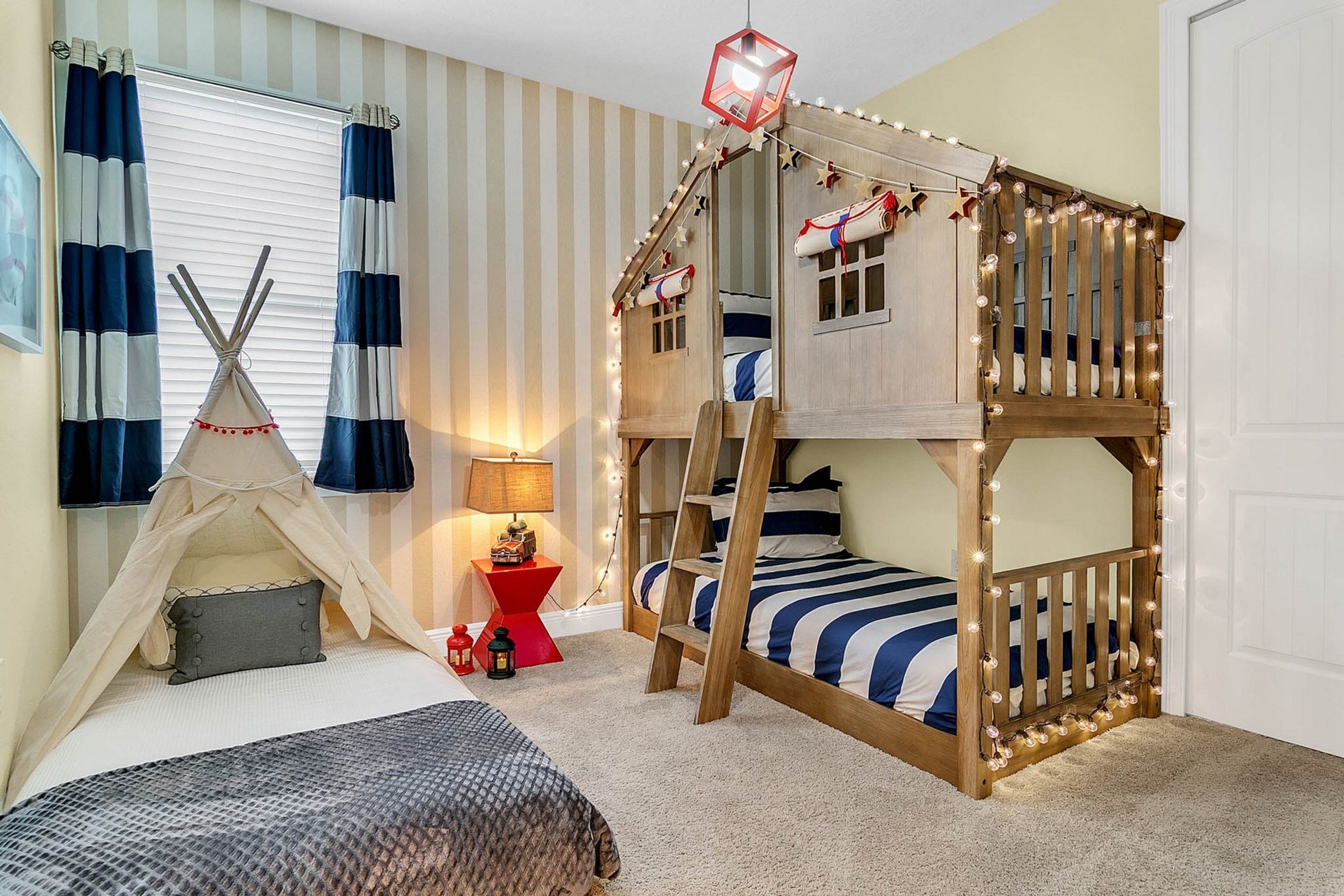 A child's bedroom with a bunk bed, a small tent, and a red side table.