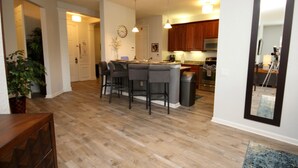 A modern kitchen with wooden cabinets, a central island with bar stools, and pendant lighting. - Vista Cay 4840 - 108 (Orlando)