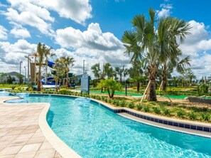 A swimming pool with a curved edge, palm trees, and a clear blue sky. - Storey Lake 4809 (Kissimmee)
