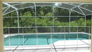 Ein überdachter Pool mit Blick auf die umliegende Grünfläche.