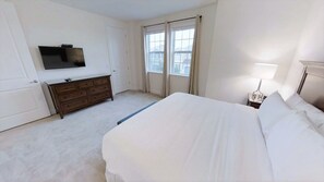 A hotel room with a bed, a dresser, a television, and a window with curtains. - Encore Resort at Reunion 7500 (Kissimmee)