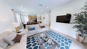 A modern living room with a sofa, coffee table, and a TV mounted on the wall. - Encore Resort at Reunion 7500 (Kissimmee)