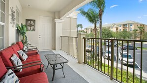 Ein Balkon mit rotem Sofa, einem kleinen Tisch und einem Deckenventilator.