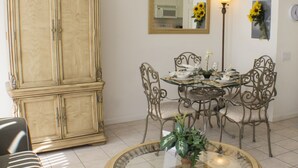 A dining area with a round glass table, metal chairs, and a wooden cabinet. - Windsor Palms 8112 (Kissimmee)
