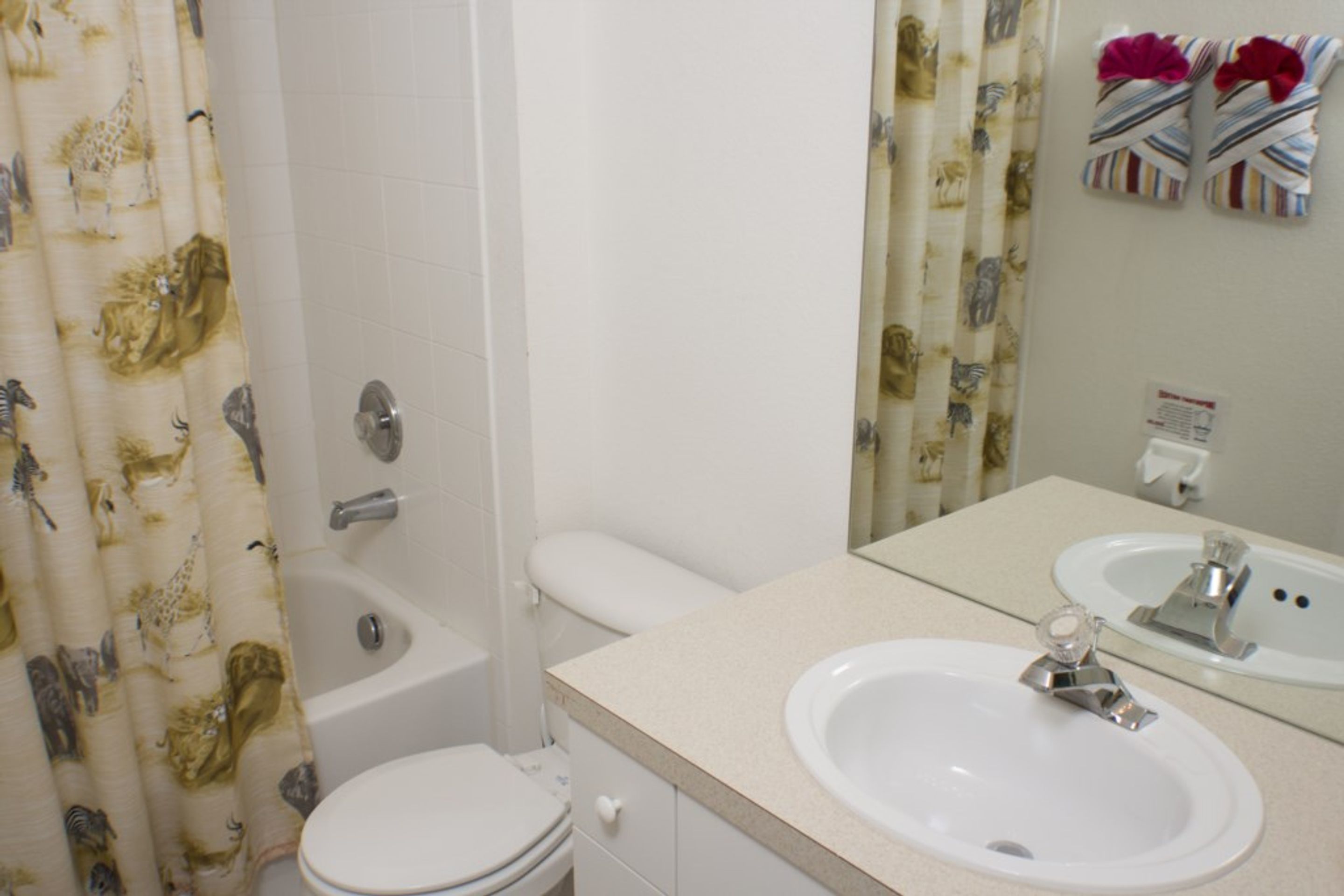 A bathroom with a toilet, a bathtub, and a sink with a mirror.