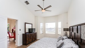 A bedroom with a large bed, a ceiling fan, a dresser, and a TV. - Tuscan Hills 353 (Davenport)
