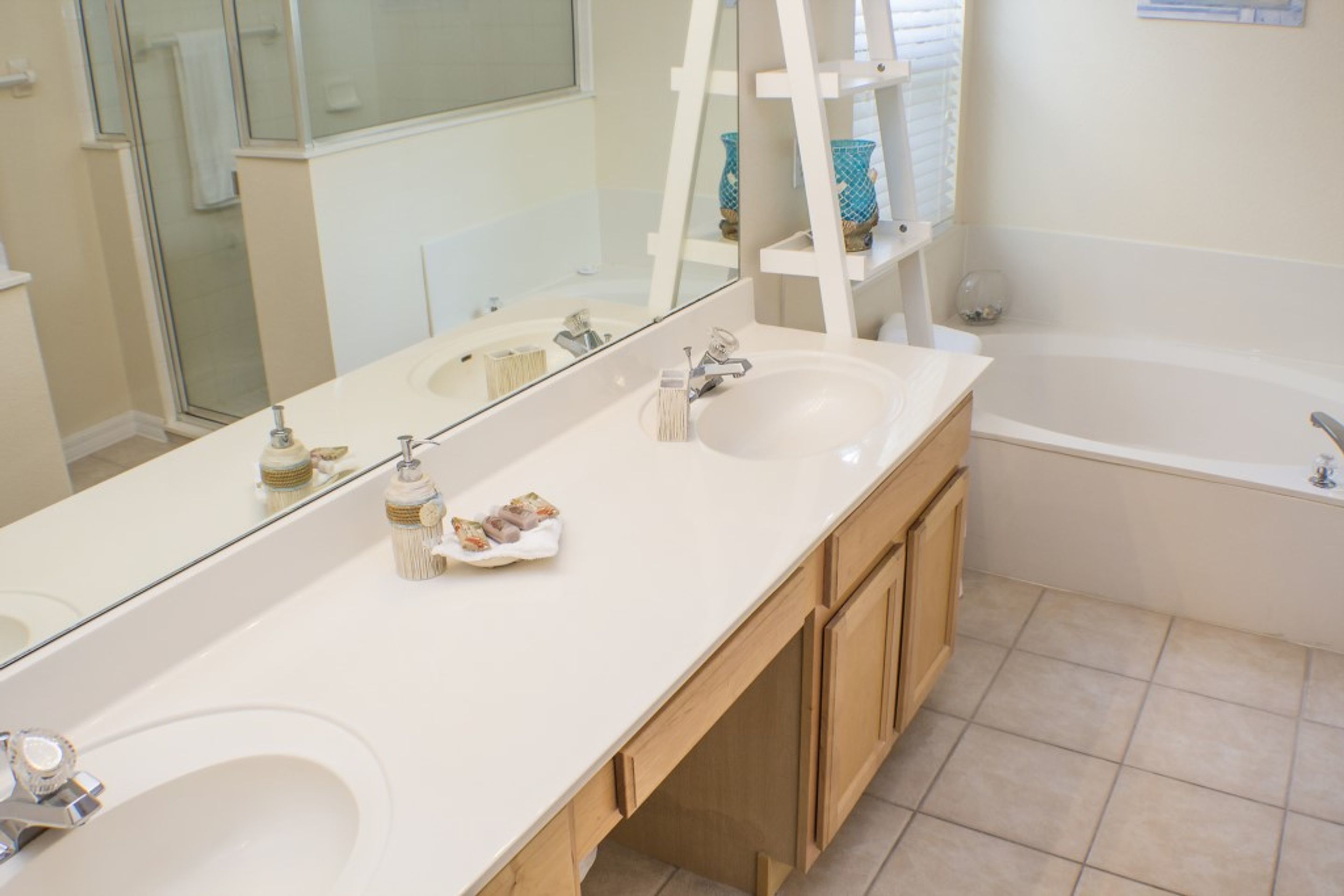 Une salle de bain avec un grand miroir, deux lavabos, une baignoire et des meubles en bois.