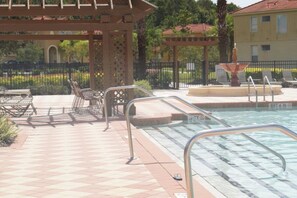 A pool area with a pergola, lounge chairs, and a fountain. - Bella Vida 4572 (Kissimmee)