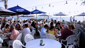 An outdoor dining area with tables and chairs, umbrellas, and a view of the sea. - Anna Maria Island 4102 - 10 (Holmes Beach)